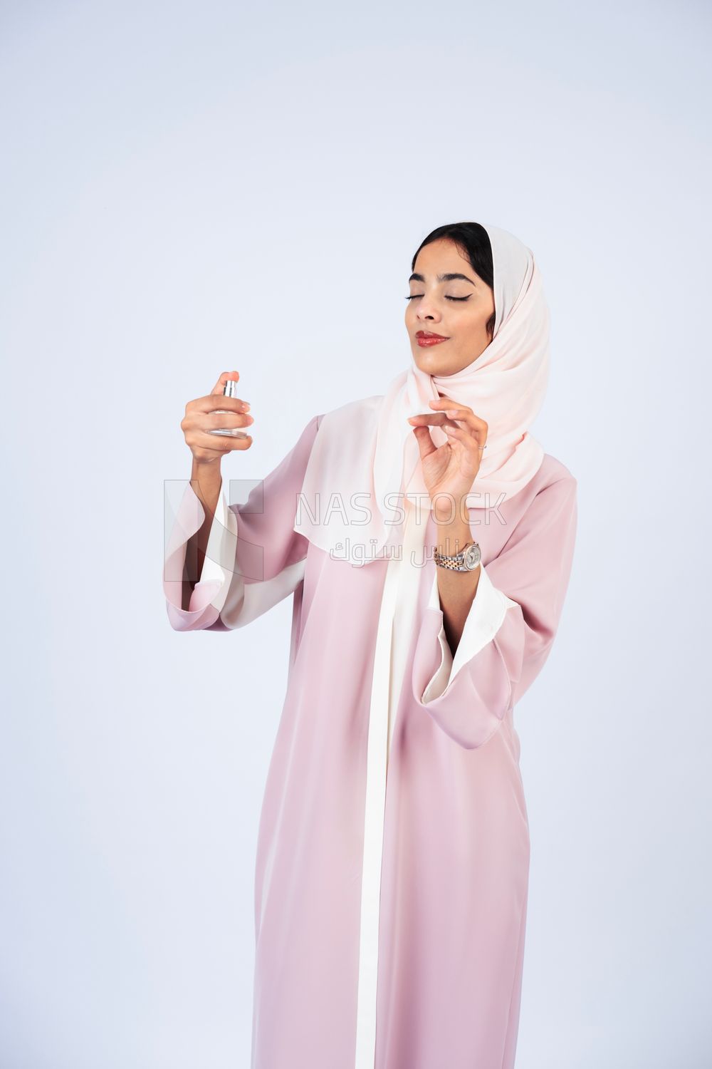 Gulf woman wearing abaya and hijab spraying perfume
