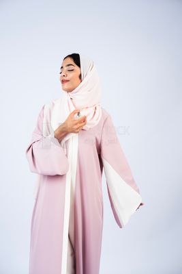 Gulf woman wearing abaya and hijab spraying perfume