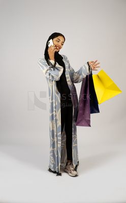 Gulf girl carrying colorful shopping bags and talking on the phone