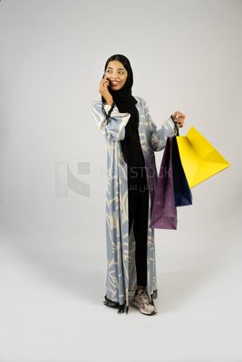 Gulf girl carrying colorful shopping bags and talking on the phone