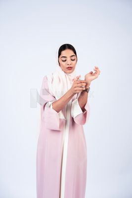 Gulf woman spraying perfume on her wrist