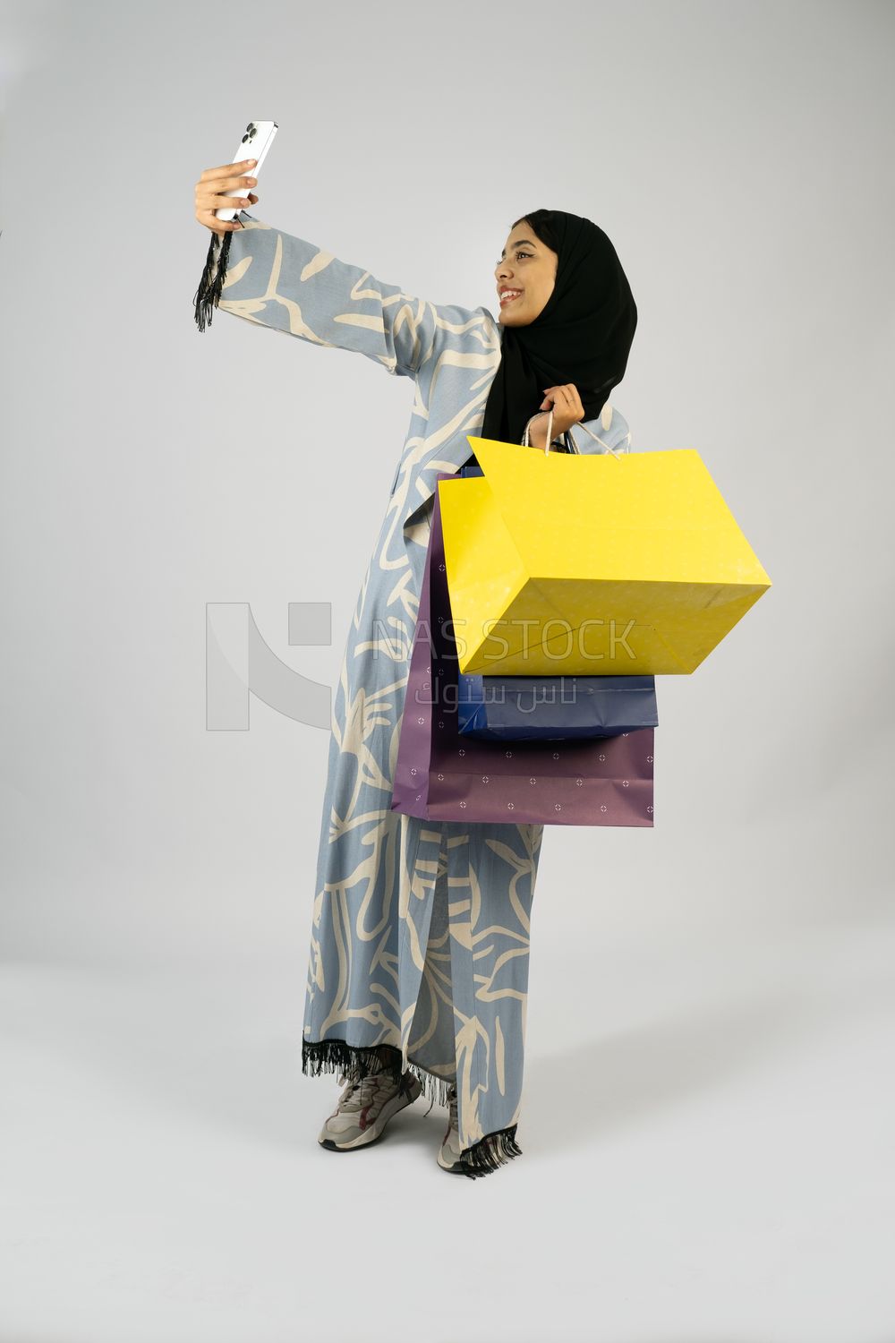 Gulf girl holding colorful shopping bags in her hand and taking a selfie