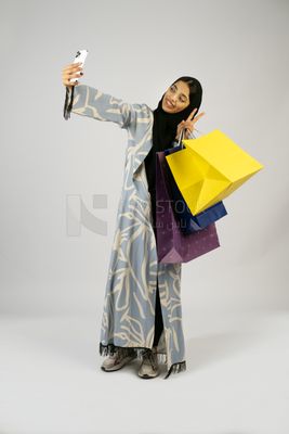 Gulf girl holding colorful shopping bags in her hand and taking a selfie