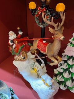 Père Noël dans son traineau survolant le village éclairé