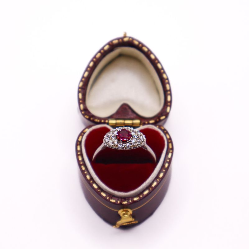 Anello in oro 18 kt con rubino centrale rosso ovale, circondato da una cornice di diamanti