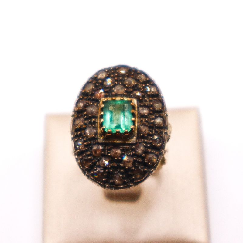 Anello in oro 18 kt con smeraldo rettangolare verde centrale e pavé ovale di diamanti.