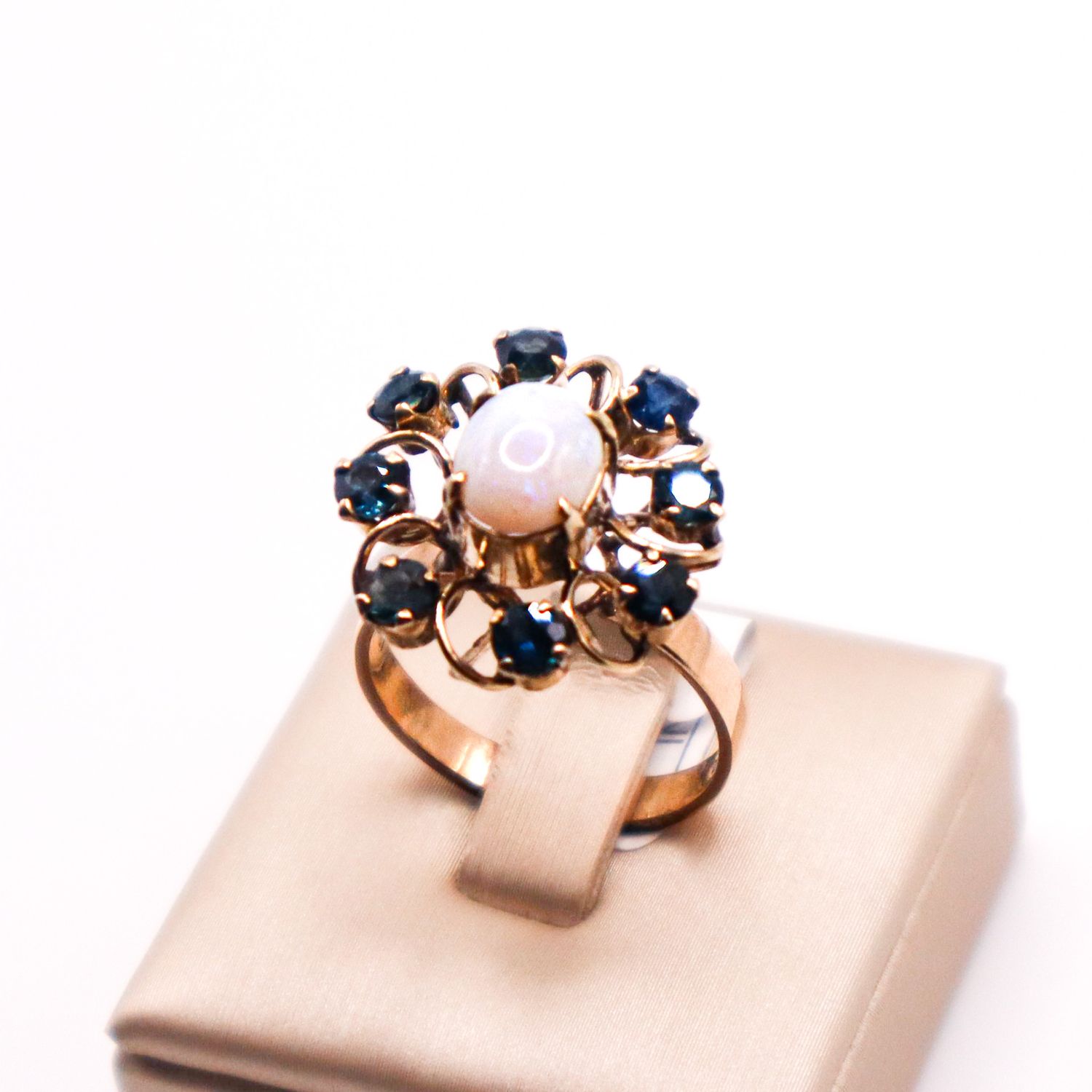 Anello vintage anni ’30 in oro 12 kt con opale cabochon centrale e contorno floreale di zaffiri blu.