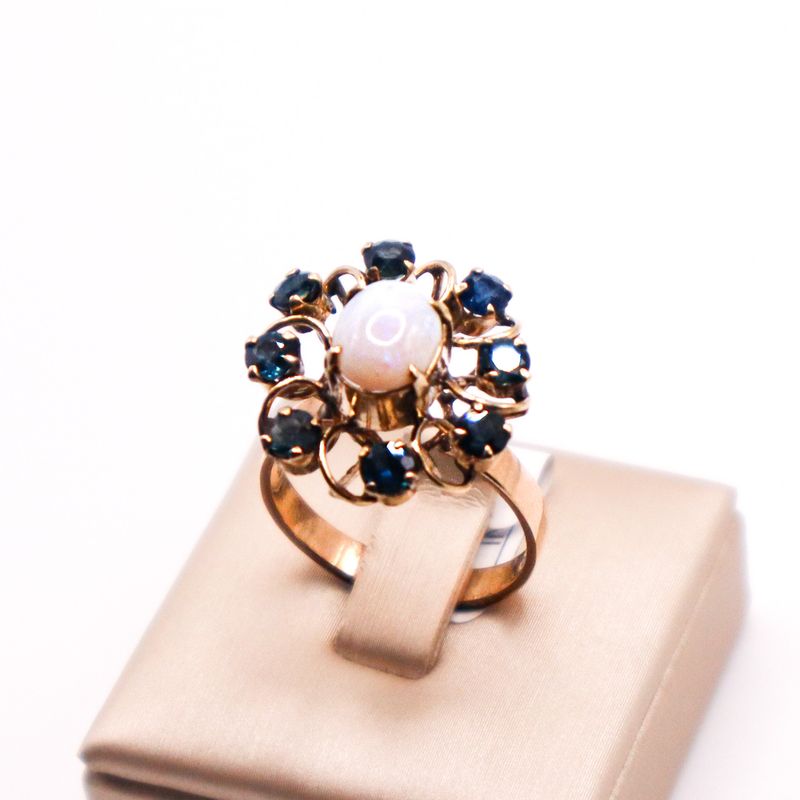 Anello vintage anni ’30 in oro 12 kt con opale cabochon centrale e contorno floreale di zaffiri blu.