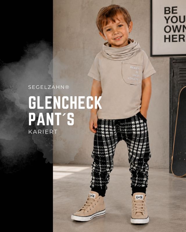 Kinderhose Kariert Glencheck | Mitwachshose Unisex für Jungen & Mädchen Junge trägt karierte Kinderhose im Glencheck-Muster in Schwarz-Weiß mit Hemd, Strickweste und Sneakern.