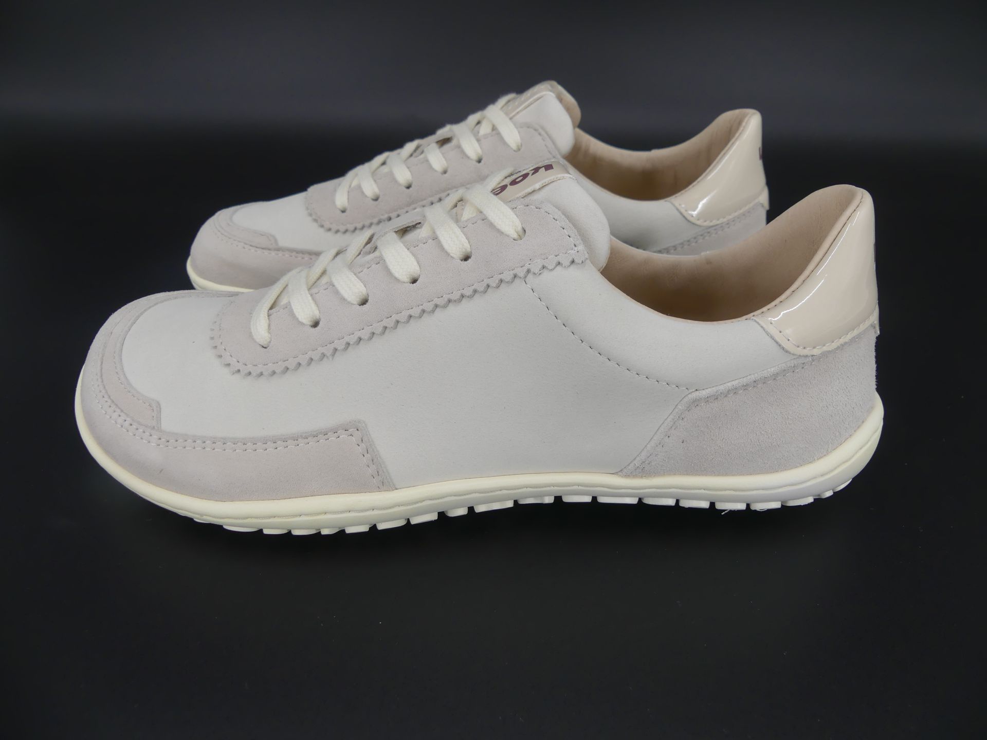KOEL Isabella Barfußsneaker in Beige – schräge Vorderansicht mit glattem Leder und schlichter Schnü…