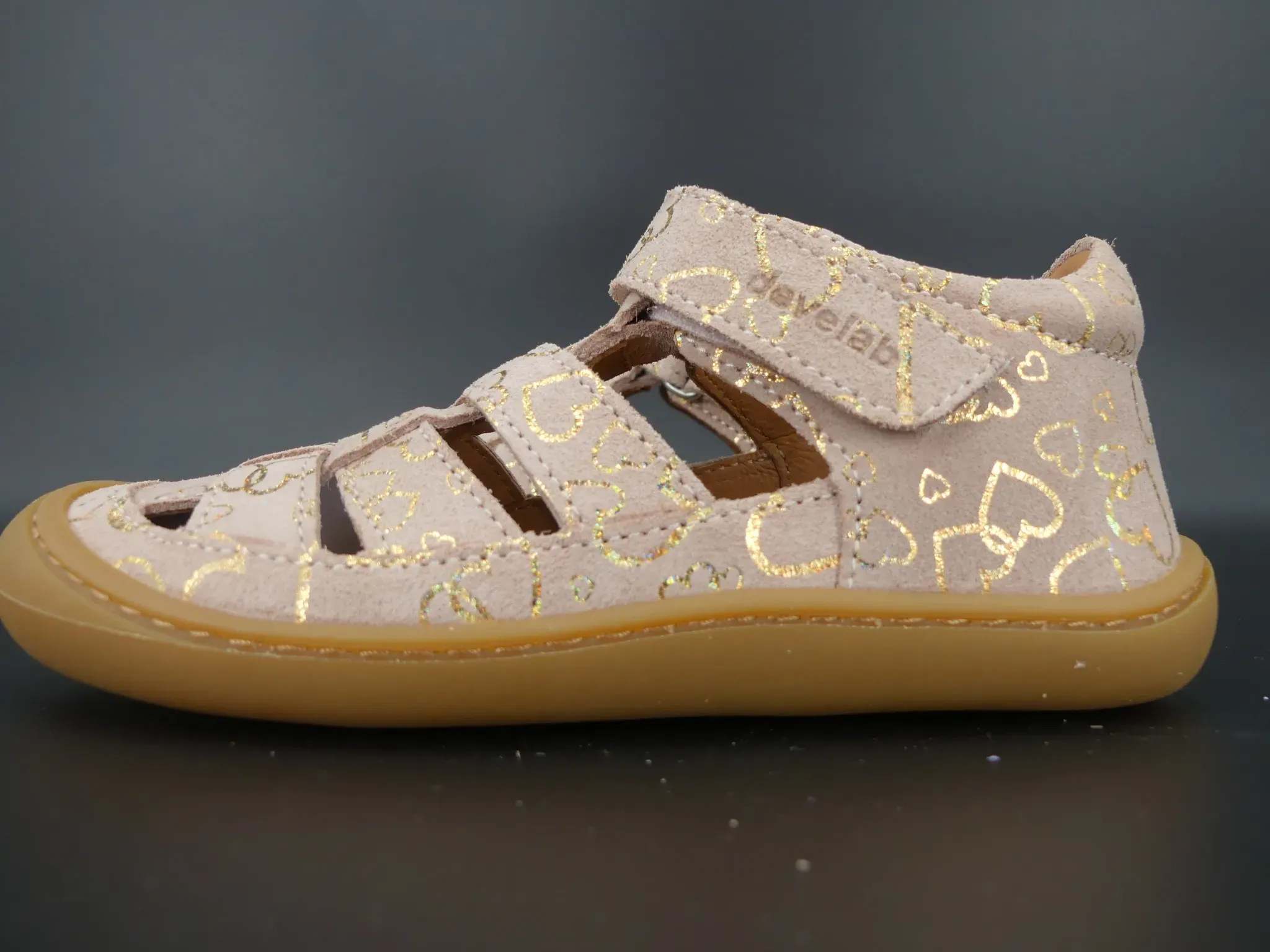 Schräge Vorderansicht der Kindersandale in Beige mit goldenen Details