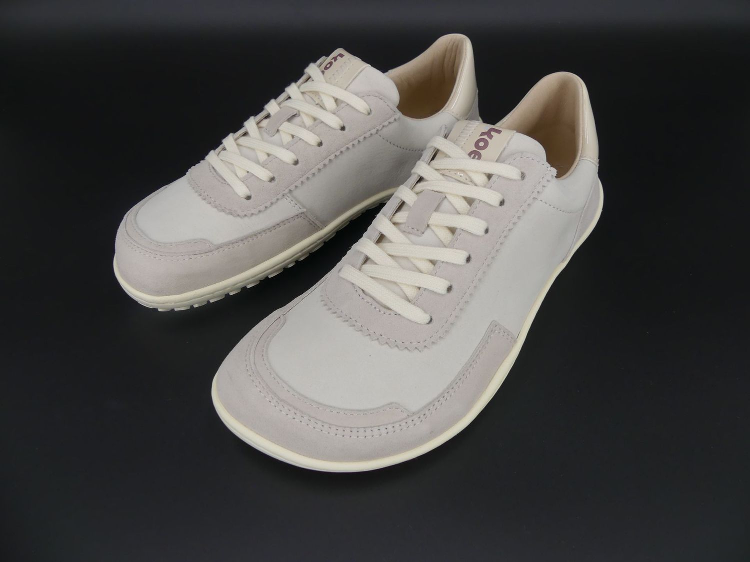 KOEL Isabella Barfußsneaker in Beige – schräge Vorderansicht mit glattem Leder und schlichter Schnü…