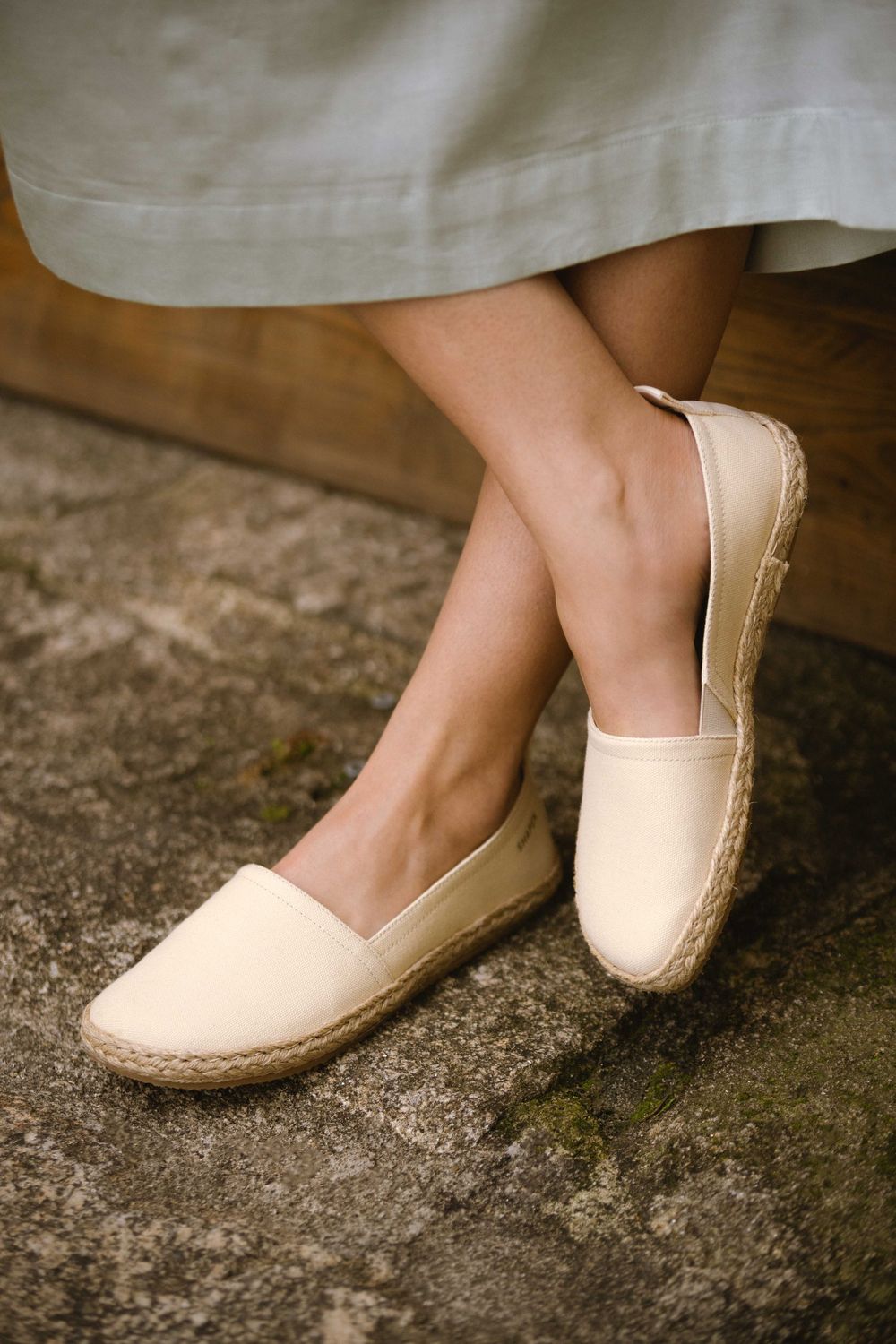 Espadrilles am Fuß im gekreuzten Sitz – entspannter Sommermoment