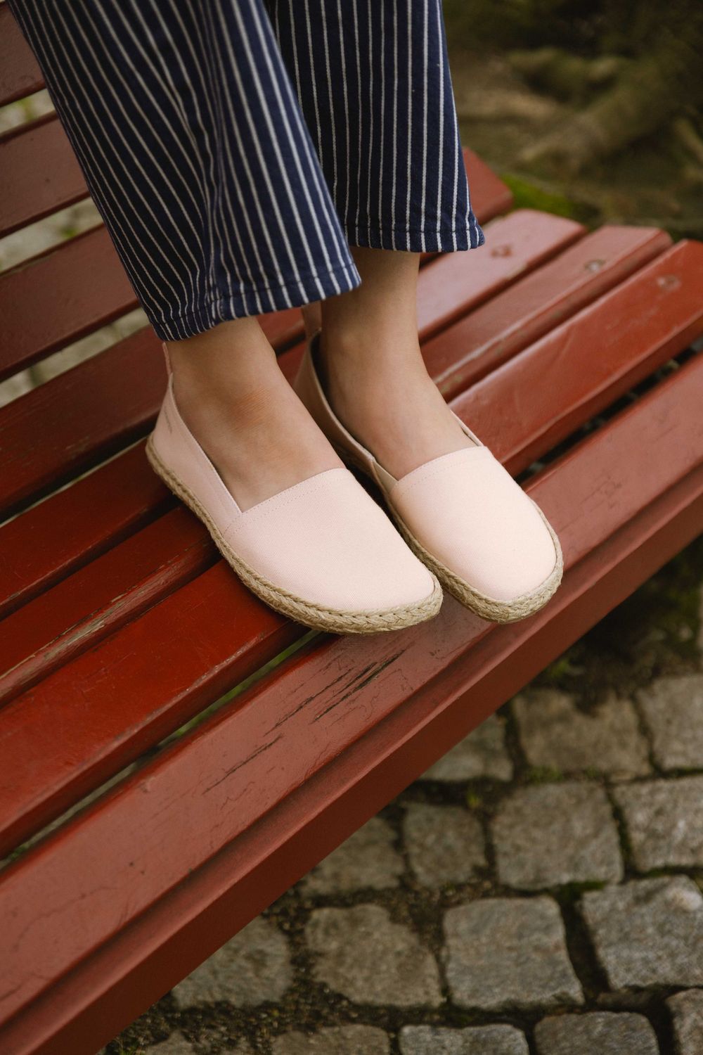 Sommerliche Espadrilles an den Füßen einer Frau – casual Look auf roter Bank