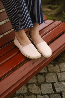 Sommerliche Espadrilles an den Füßen einer Frau – casual Look auf roter Bank