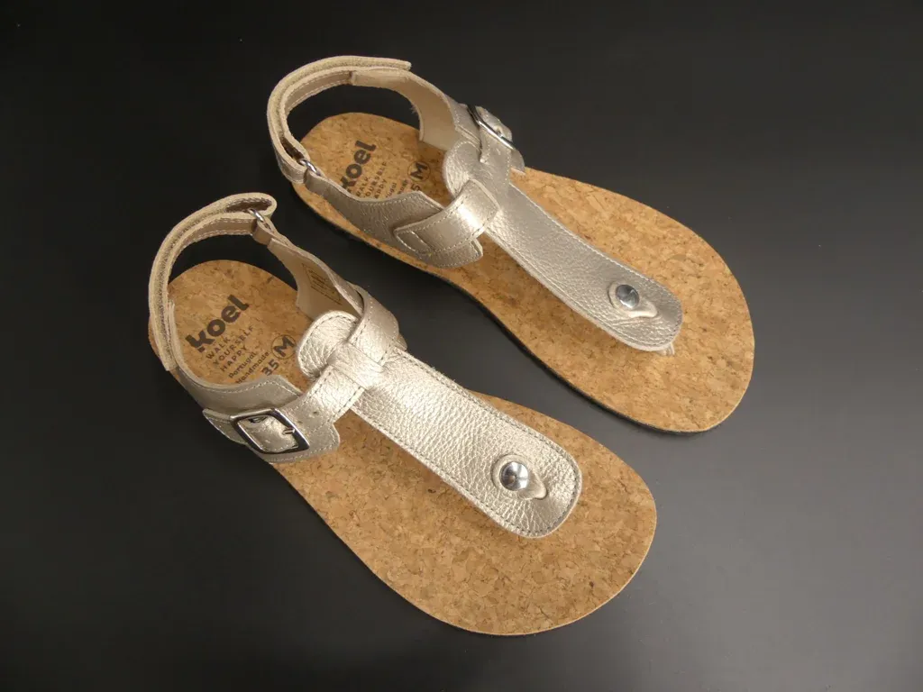 Seitenansicht der KOEL Abriana Barfußsandale in Champagner – flacher Sitz, schmale Riemen, flexible…