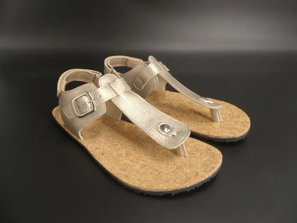 Seitenansicht der KOEL Abriana Barfußsandale in Champagner – flacher Sitz, schmale Riemen, flexible…