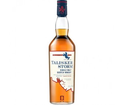  Uma garrafa de Talisker Storm, com seu design marcante e cor âmbar profunda, ao lado de um copo de uísque com um cubo de gelo, sobre um fundo de pedras e ondas do mar.