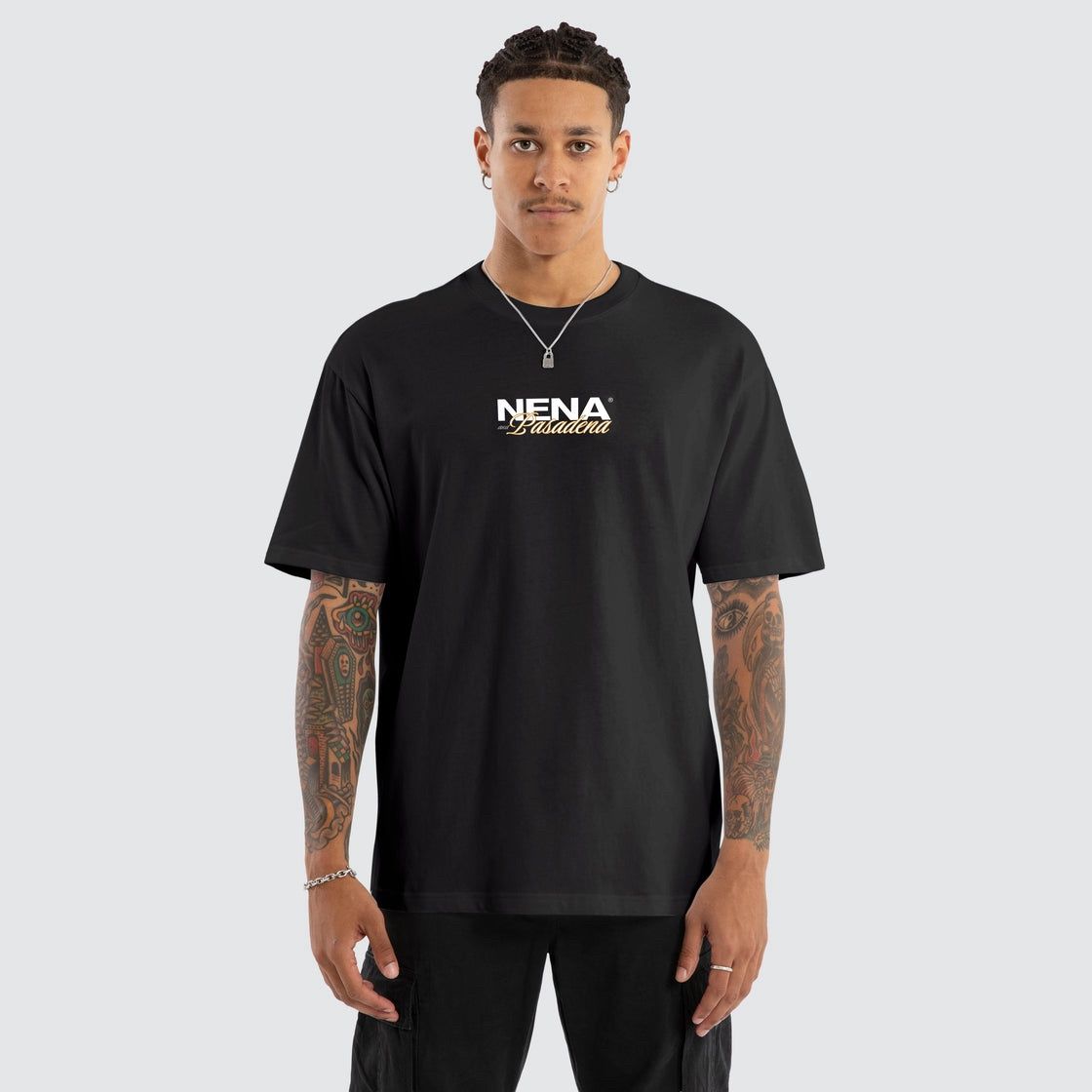 A male model wearing the Nena and Pasadena NXP Demand Box Fit Tee in black, featuring a white and gold chest logo.
