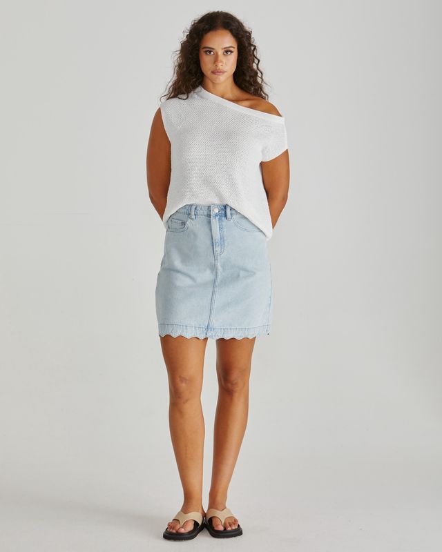 Full-length front view of the white knitted Jaci top paired with a light blue denim mini skirt