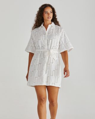 Model wearing the white Sass Dillon shirt dress, showcasing the intricate cut-out broderie pattern and tie-waist detail.