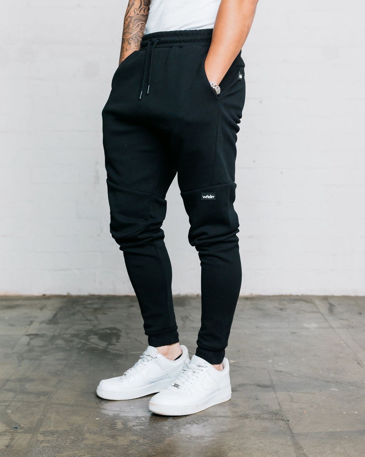 man wearing black hoxton trackpants. showing the generous pockets 