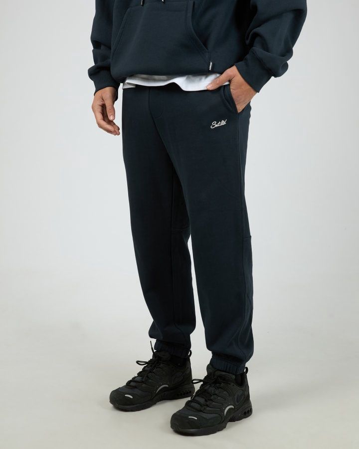 Man wearing the Radio Sweatpant in Navy featuring a small white printed logo functional pockets