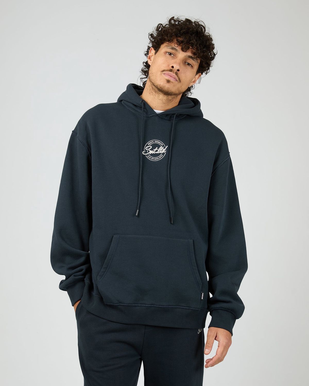 Man wearing the Radio Hoodie by St Goliath in navy featuring a navy colour and white embroidery logo on the chest
