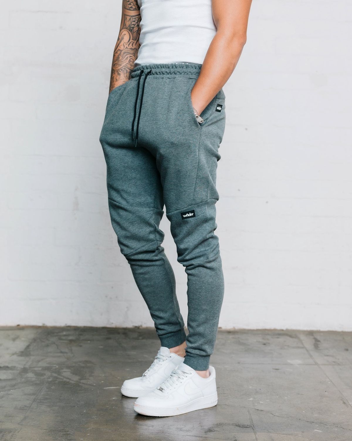 Mens dark grey trackpants with cuffed bottoms and black rubber WNDRR logo 