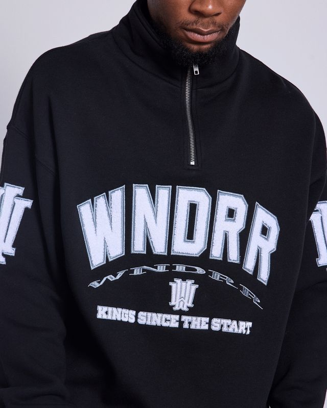 Close up of man wearing the Wndrr Institute 1/4 Zip Sweat featuring a bold white Wndrr logo on the front and W on the sleeves