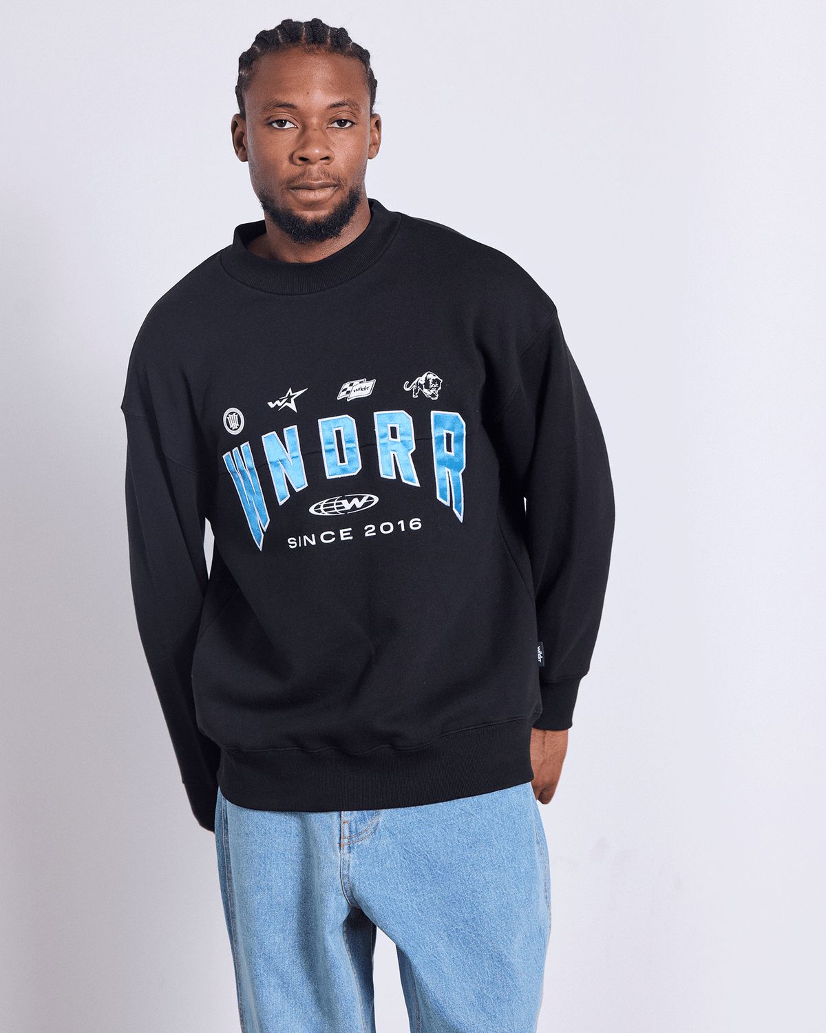 Man wearing the over sized WNDRR Hashi Crew Sweat in black with blue WNDRR branding on the front 