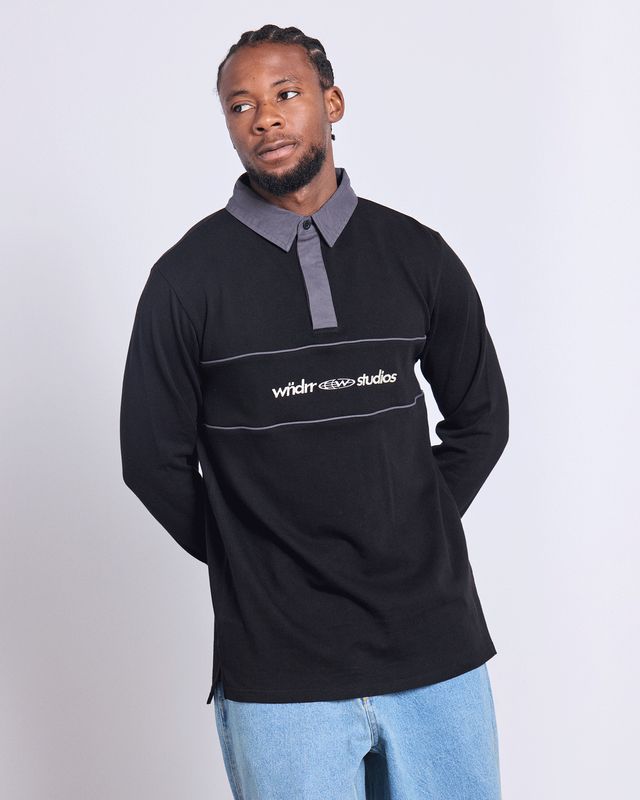 Man wearing the WNDRR Globe Rugby in black and grey showing white wndrr branding across the chest 
