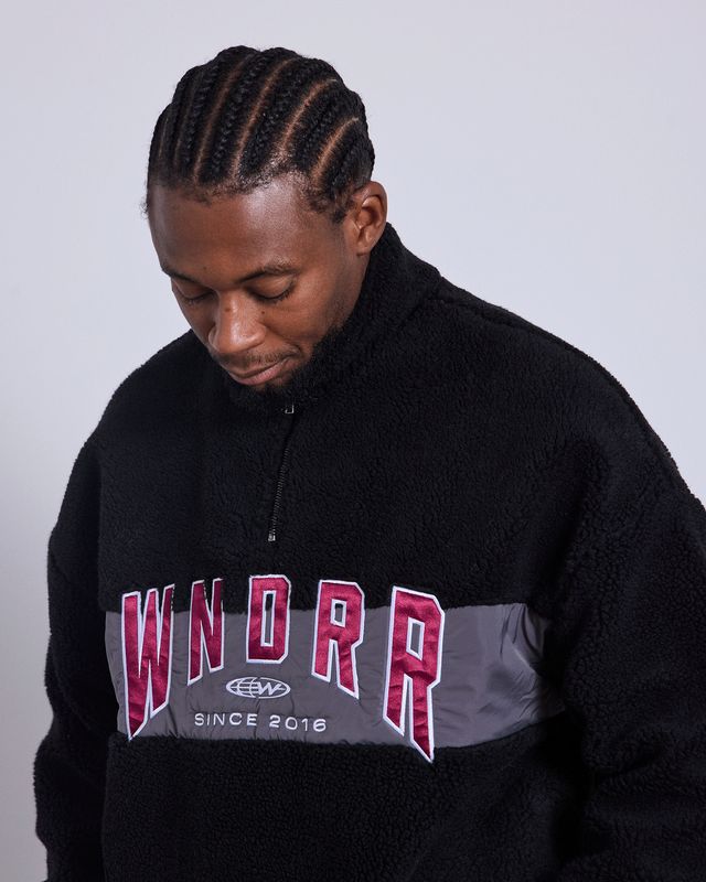 close up of a man wearing the WNDRR Hashi 1/4 Zip Sherpa Fleece showing the soft sherpa fleece, grey panel and red logo 