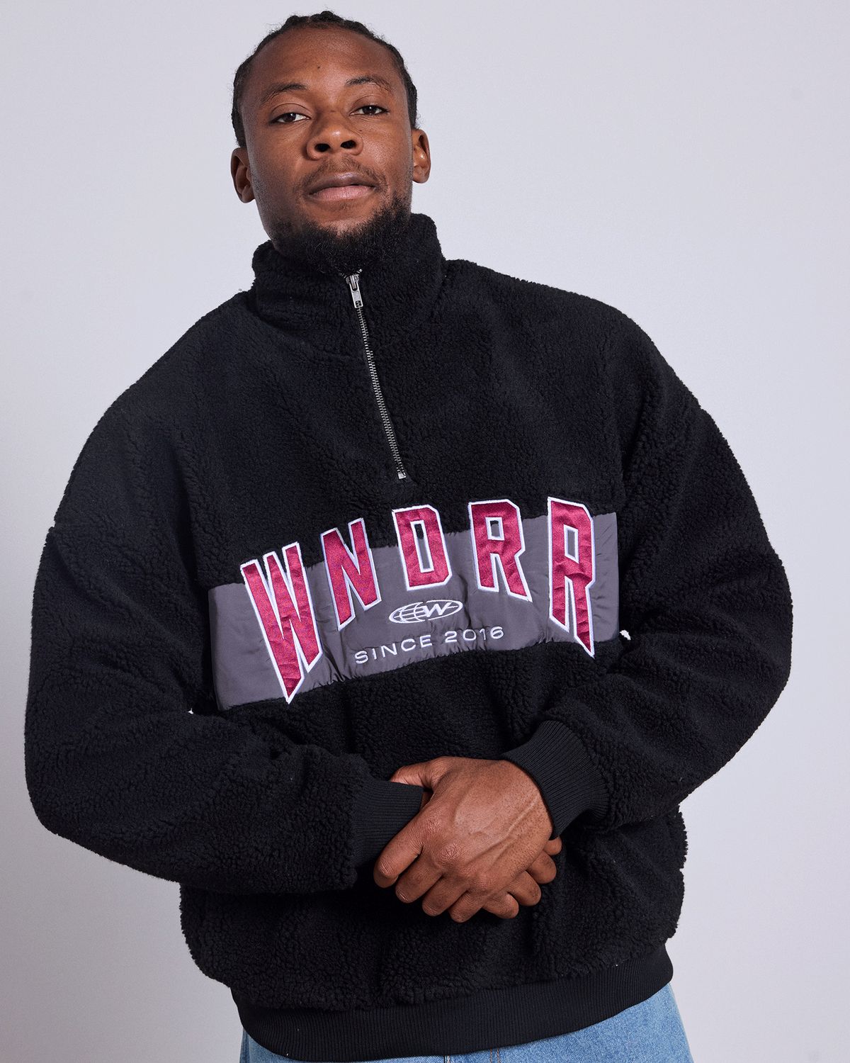 Man wearing the WNDRR Hashi 1/4 Zip Sherpa Fleece jacket in black featuring a warm sherpa fleece and grey panel across chest