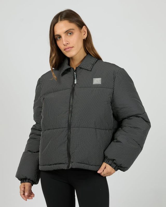 Women model wearing the In Check Puffer showing the AAE rubber logo, functional zip and cuffed sleeves 

