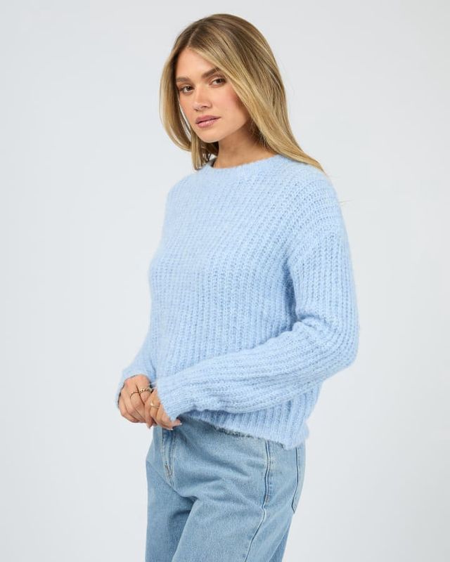 Side view of the a women wearing the All About Eve Ivy Knit Jumper featuring cuffed sleeves and waist band in a blue colour