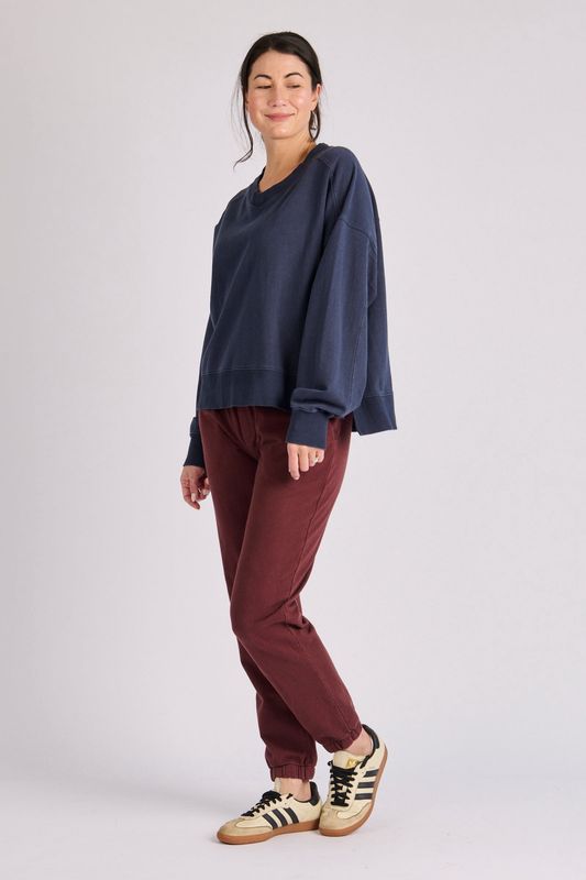 Full body view of the V Neck Boxy Crew in Indigo matching it back with a pair of burgundy trousers for the comfiest look