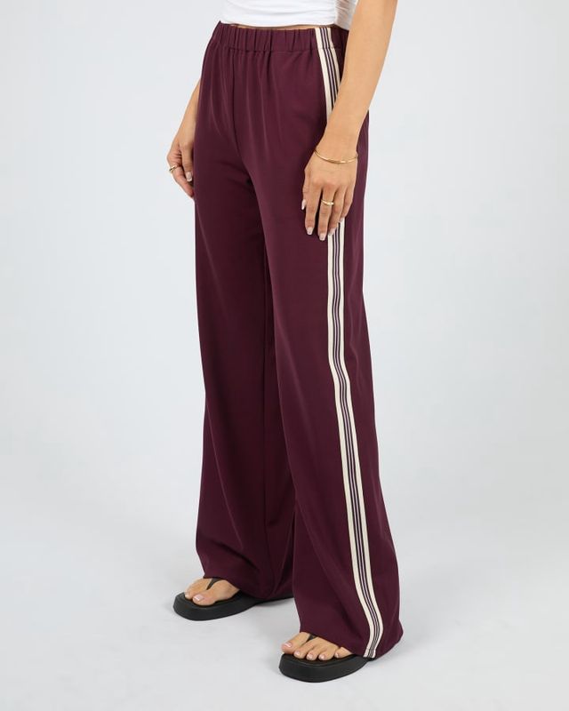 Women wearing the Lina Pant in Wine from All About Eve with wine and cream ribbon stripes down the side of the leg