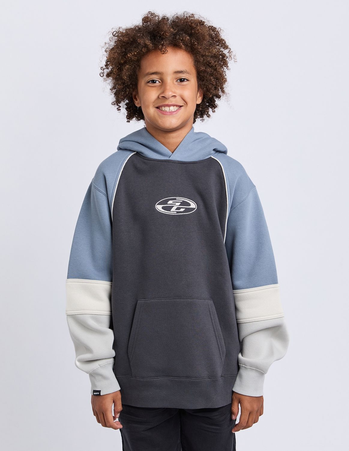 Teen Model wearing the St Goliath Quantum Hoodie in charcoal with cream and blue paneling 