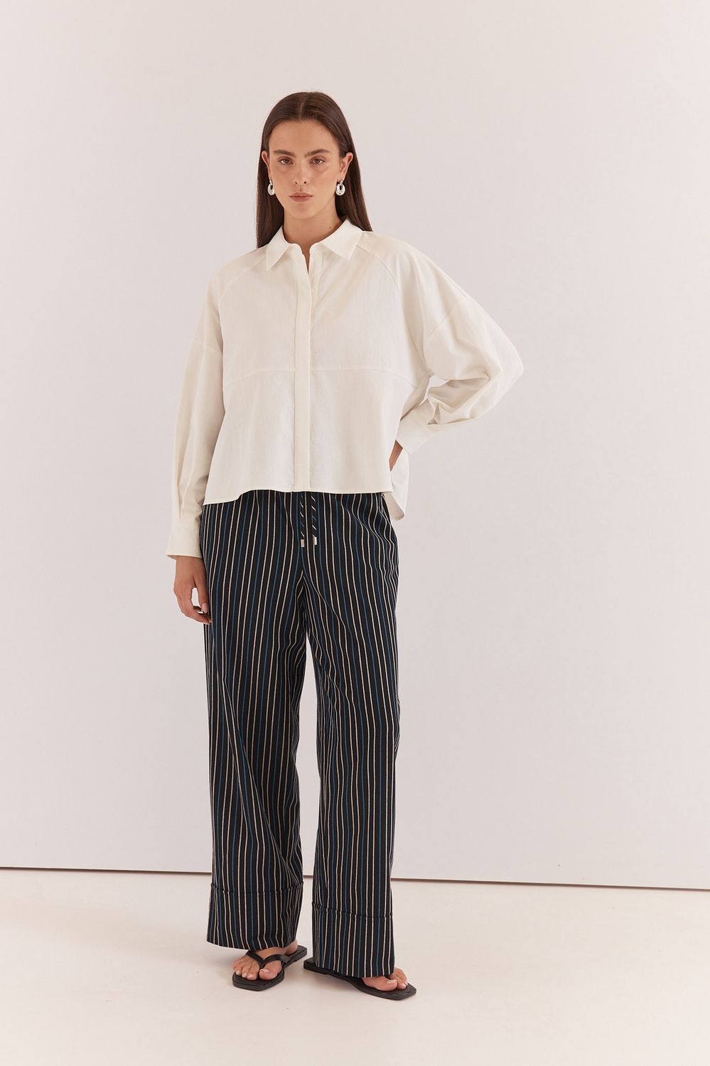 Full body view of the Sass Ashby Peplum Shirt. Matching it back with a pair of black and white stripe work pants
