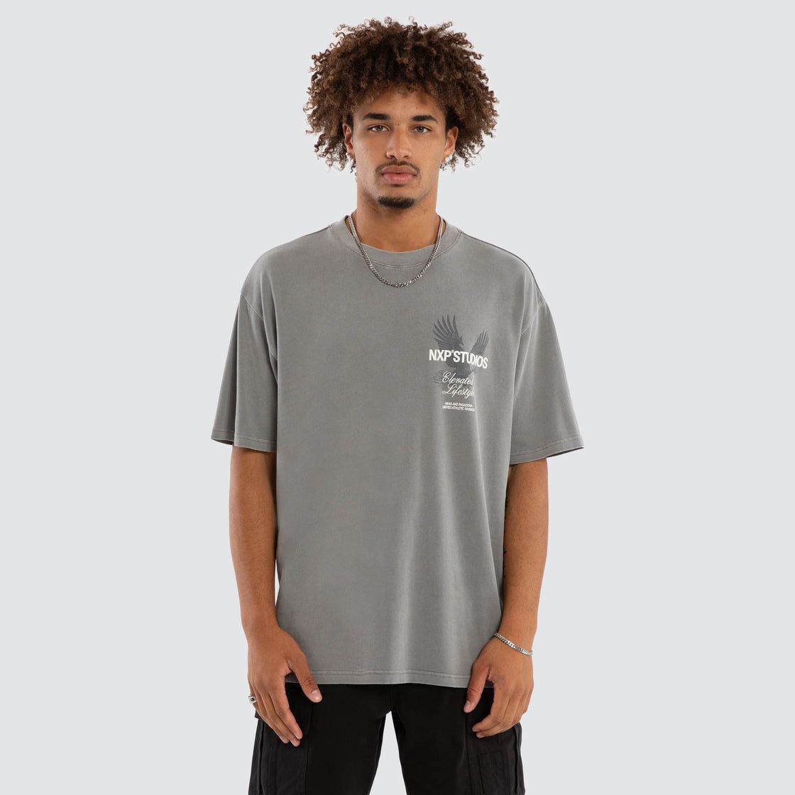 A male model wearing the NXP Moros Box Fit Tee in light grey.

