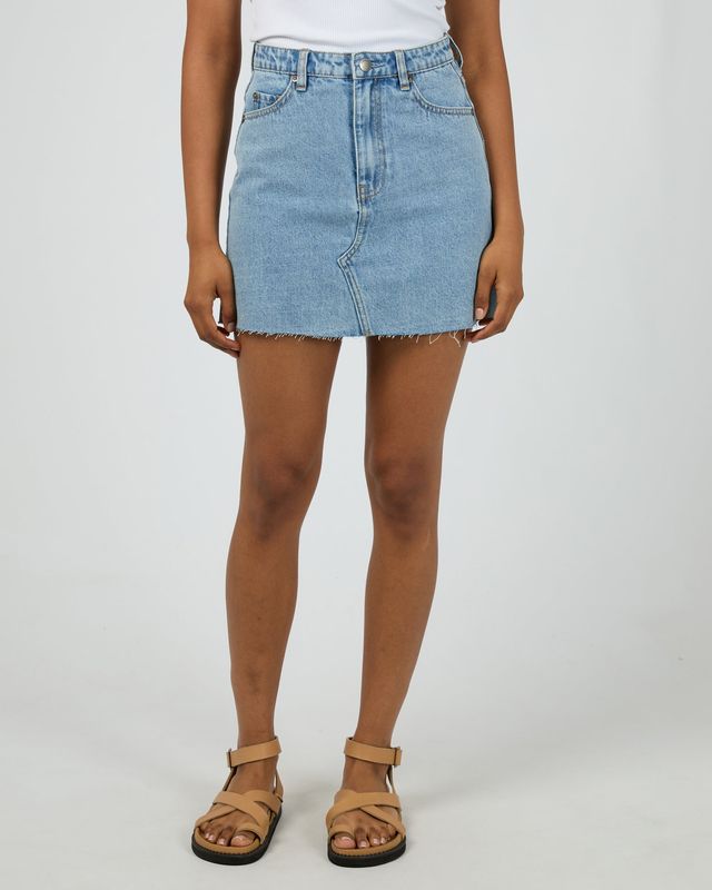 A female model wearing the Margot Denim Skirt featuring the mini length fit and medium weight material.