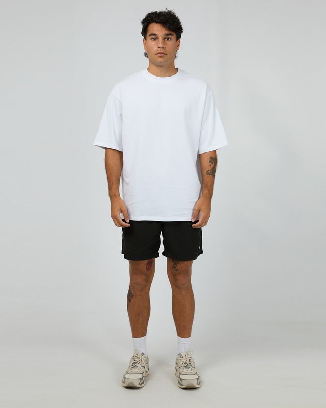 Close up of a male model wearing the ILLUSION Short in Black, featuring a small ST.G logo and two function pockets.