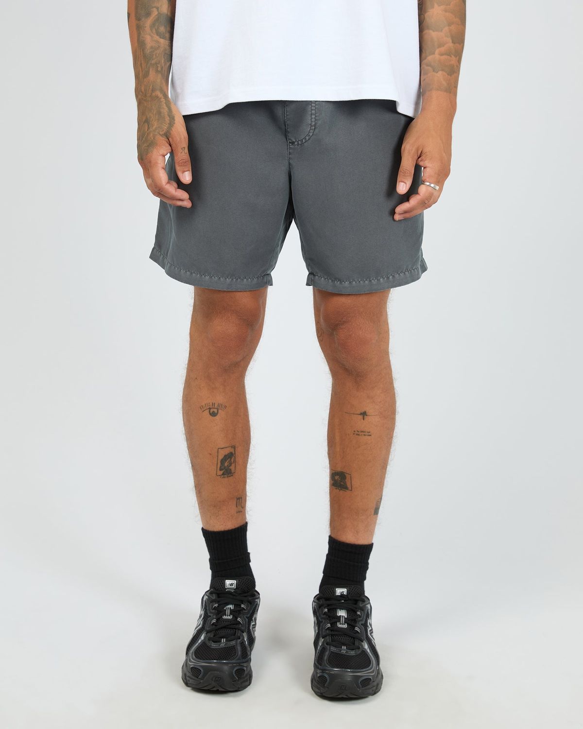 A male model wearing the ILLUSION Short in Coal, featuring light weight material and soft to the touch.