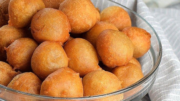 Freshly fried puff-puff, golden and fluffy deep-fried dough balls, ideal for snacking or sharing at gatherings.