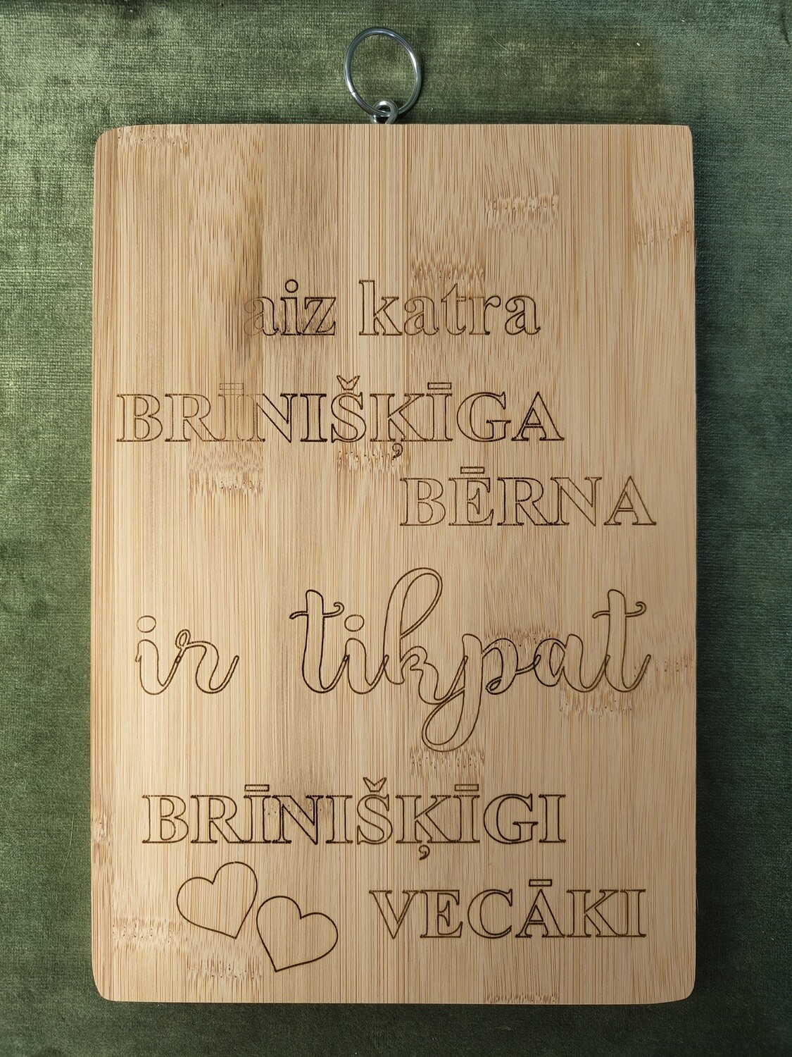 Virtuves dēlis 29x20 ar gredzenu &quot;Aiz katra brīnišķīga bērna ir tikpat brīnišķīgi vecāki&quot;