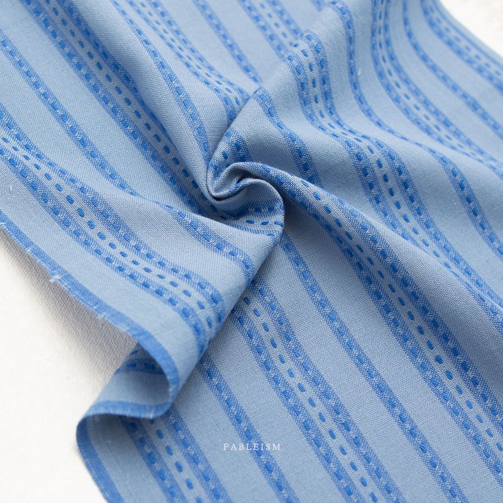 Gewebter Baumwollstoff Stitch Stripe in Blue von Fableism aus der Kollektion Fine and Dandy mit blauem Streifenmuster.