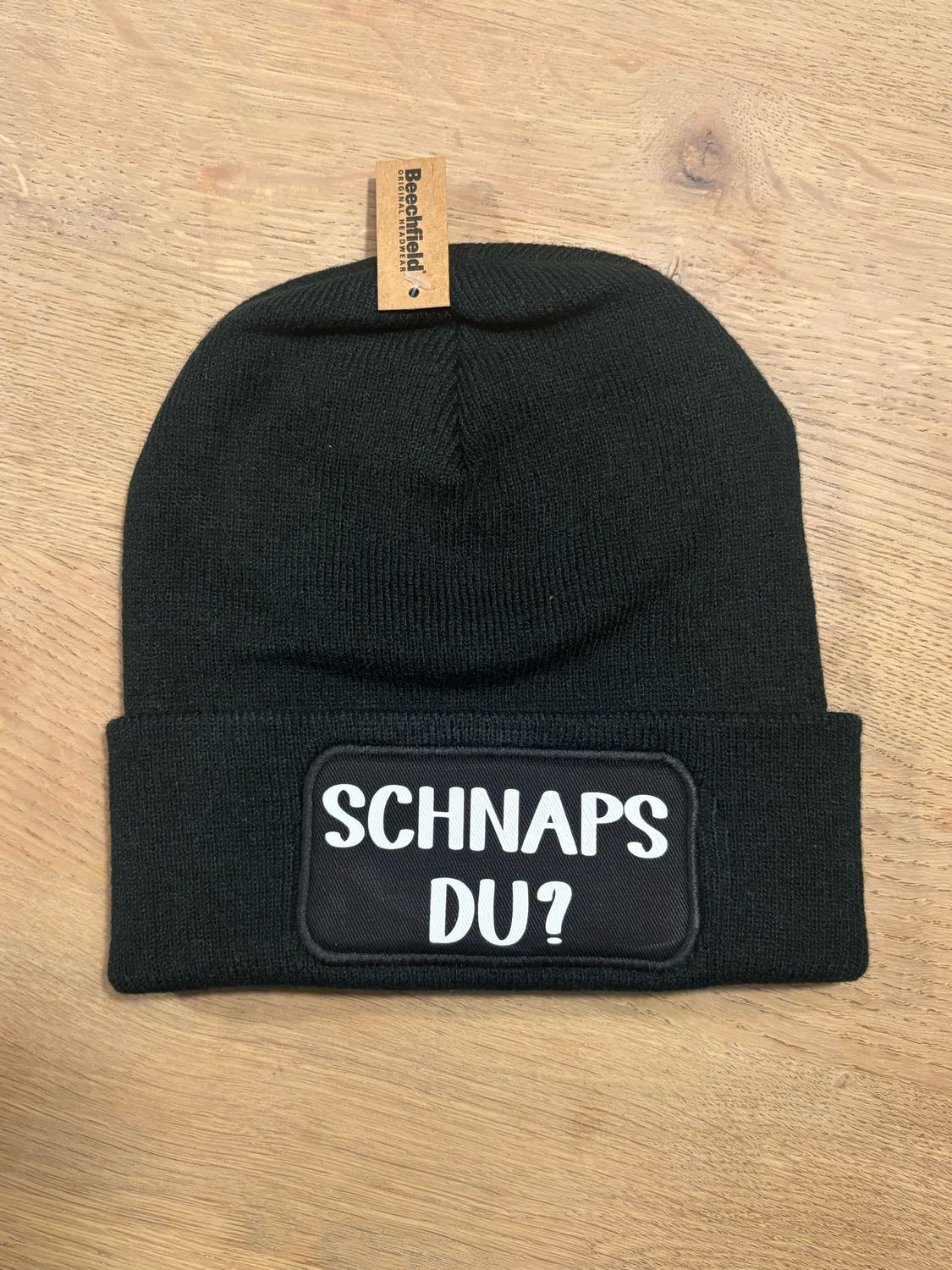 Muts / Beanie met tekst Schnapps du? Zwart met witte letters
