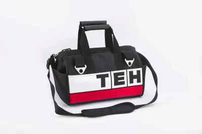 Black and red tool bag with TEH logo, rubber grip handle, shoulder strap, and multiple pockets, made of heavy-duty canvas, 14-inch size.