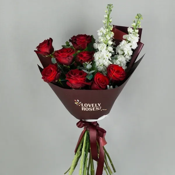 The bouquet is arranged with red roses and white petals.